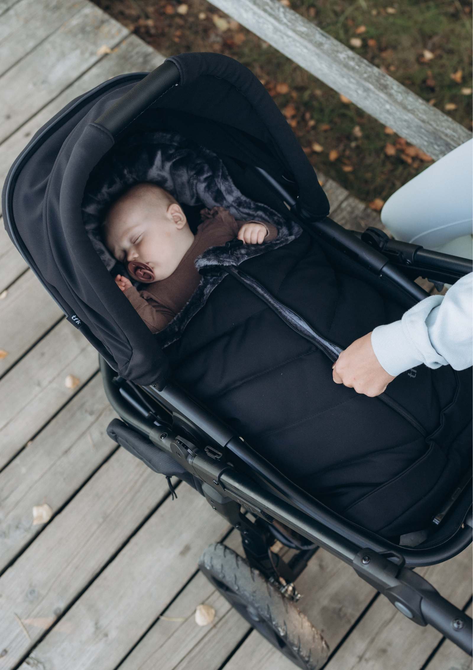 Baby liegt in TFK Kombi-Kinderwagen 'Mono 3' Schwarz