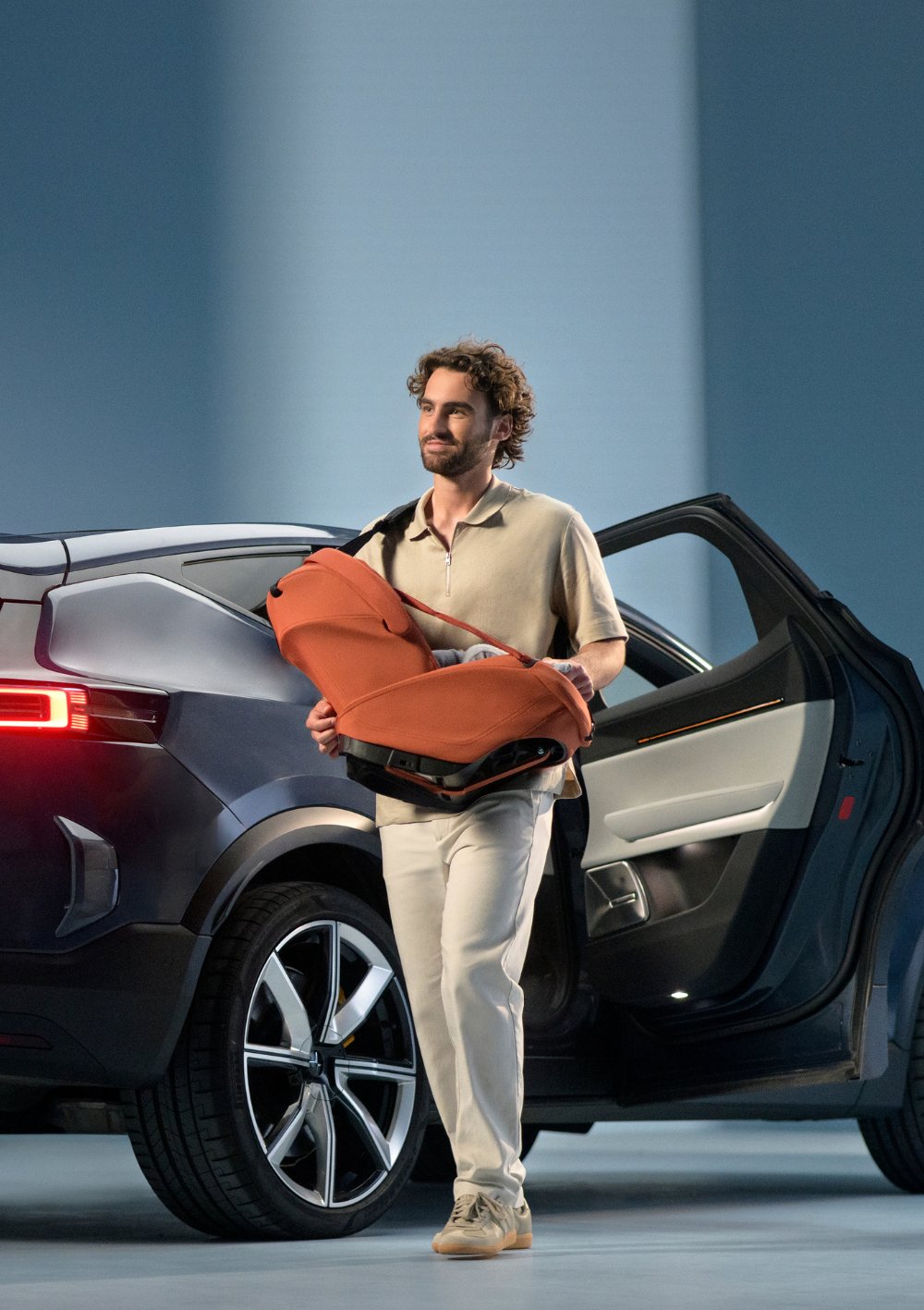 Mann trägt Maxi-Cosi Babyschale 'Coral Slide Pro' Copper Terra mit Tragegurt