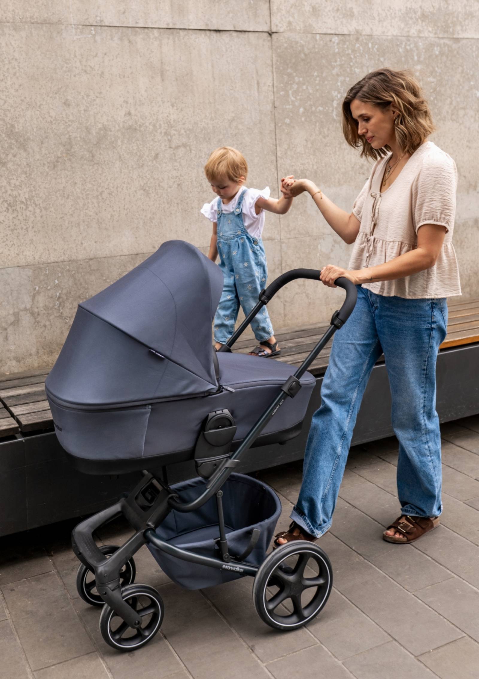 Frau unterwegs mit Kleinkind und Baby mit Easywalker Kinderwagen-Set 'Harvey NXT' Deep Blue inkl. Regenverdeck