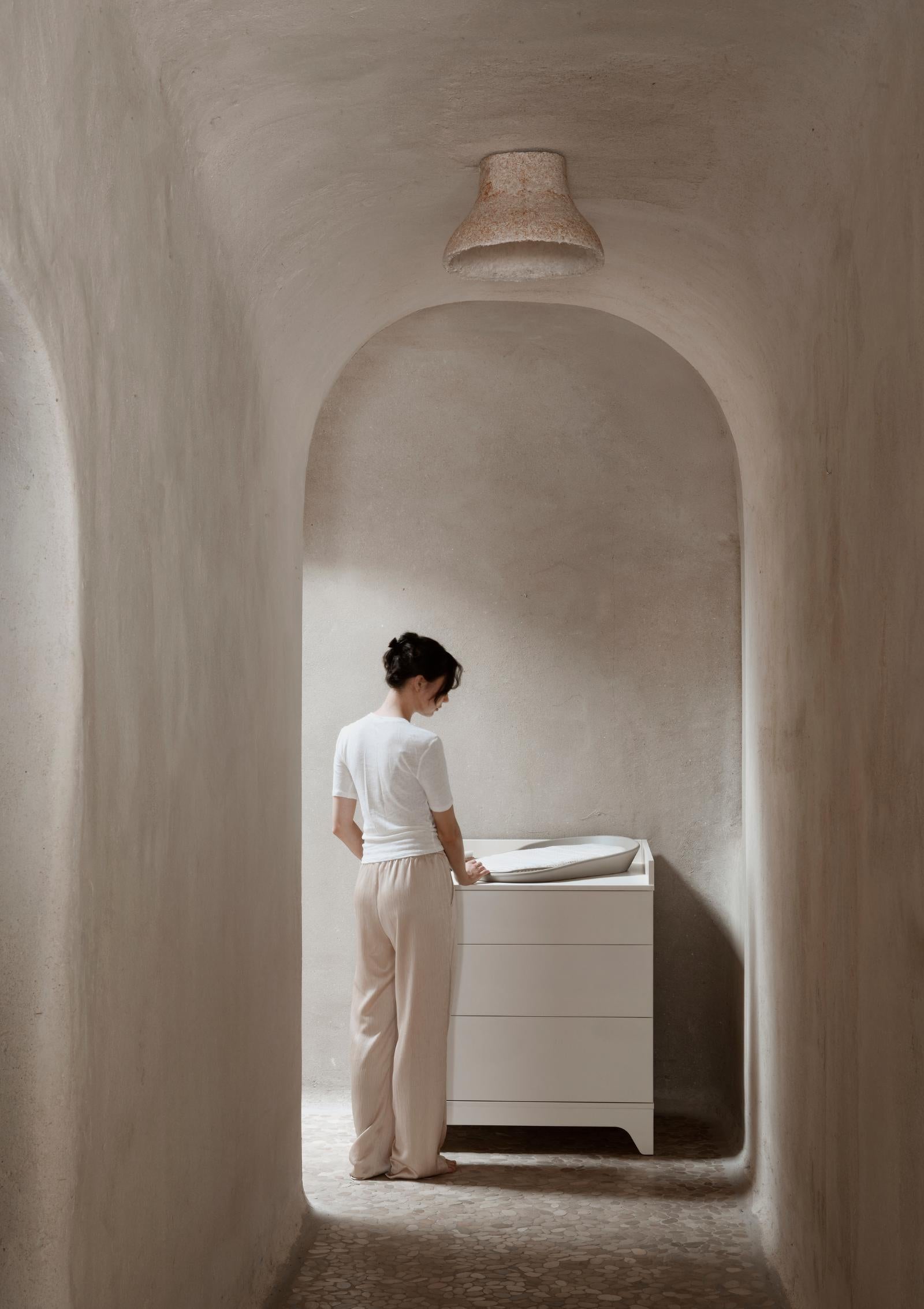 Frau steht an Quax Kommode 'Tsugi' Butter mit Wickelaufsatz