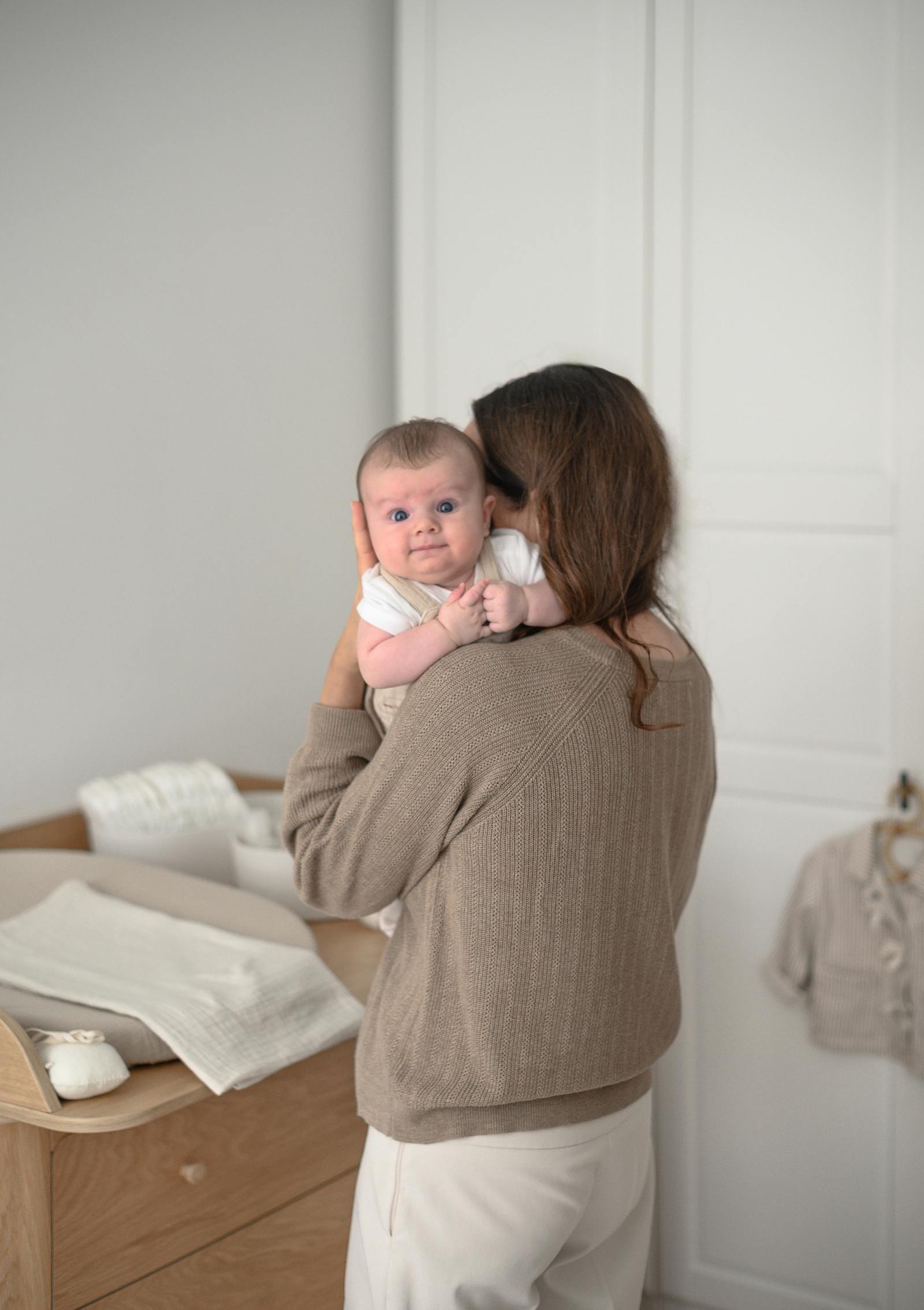Frau mit Baby, im Hintergund: We Are Bitte (Wickel-)Kommode 'Nature Dresser 2.0' Eiche