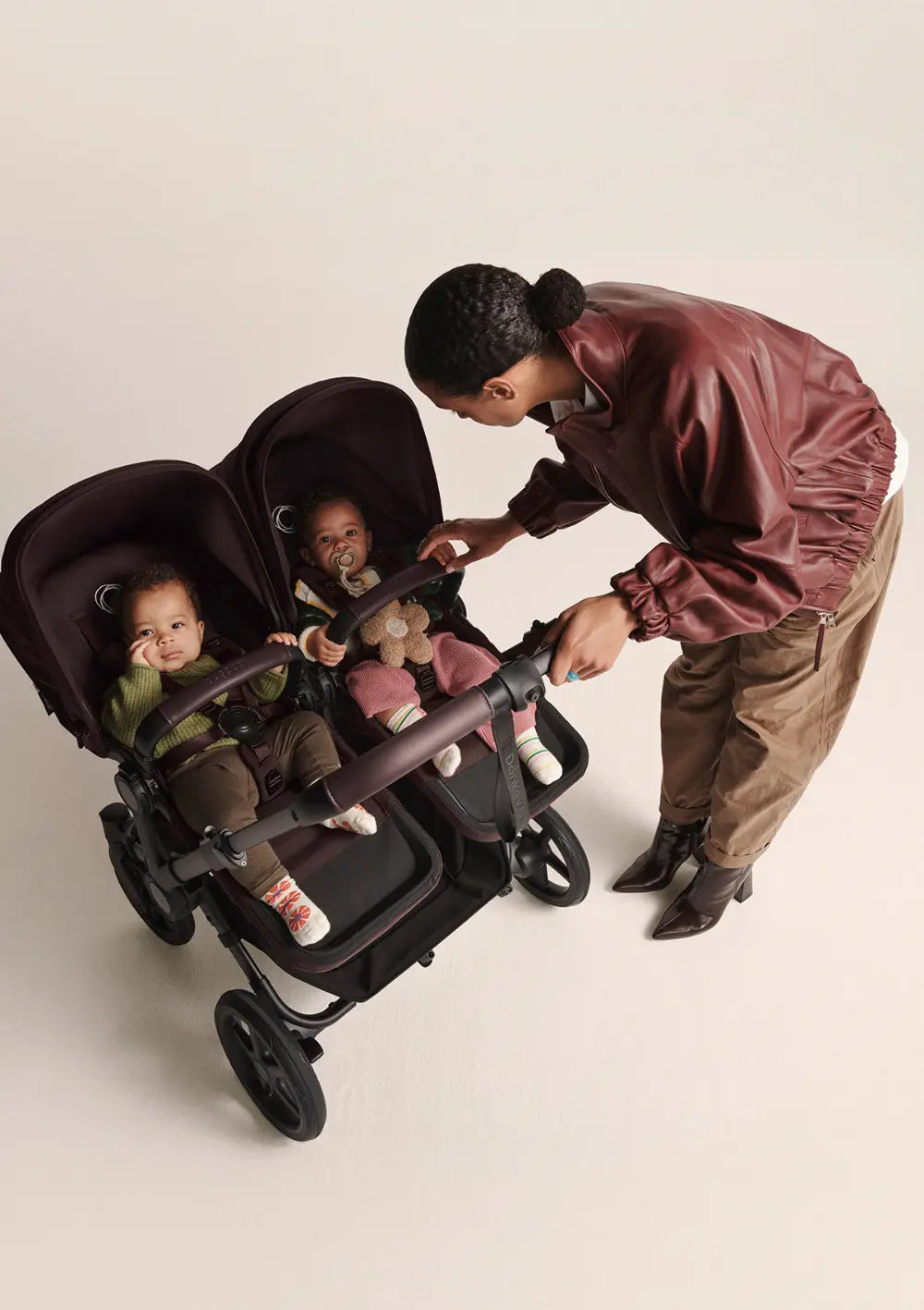 Frau beugt sich zu ihren Kindern im Bugaboo Zwillingskinderwagen 'Donkey 6 Twin' Cocoa Brown