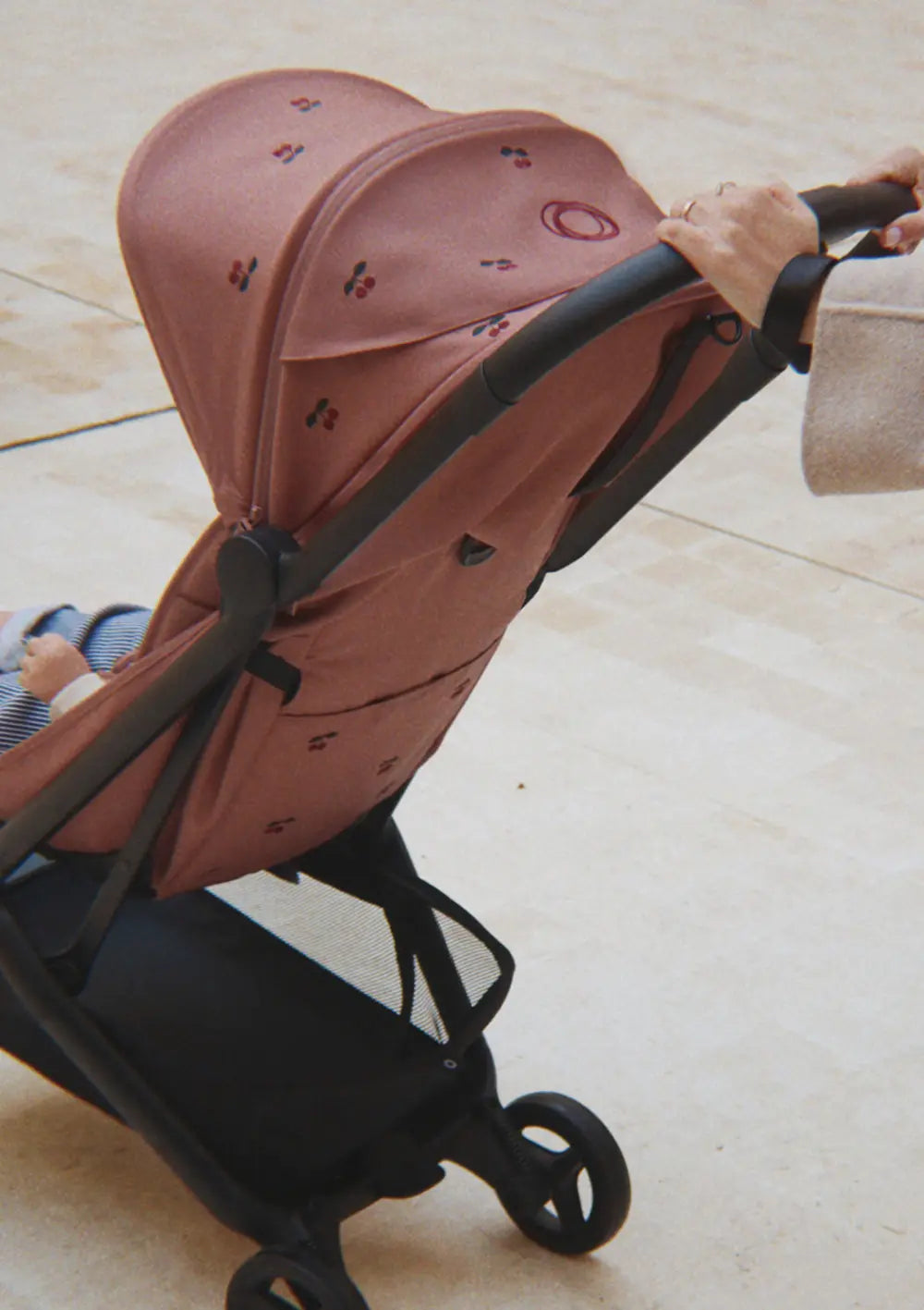 Eine Frau schiebt ihr Kind im Bugaboo Buggy 'Butterfly 2 x Konges Sløjd' Dusty Pink / Cherry