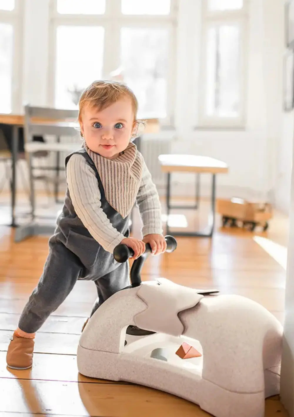 Kleinkind steht am Scoot and Ride 3-in-1 Babyroller 'My First' sand 
