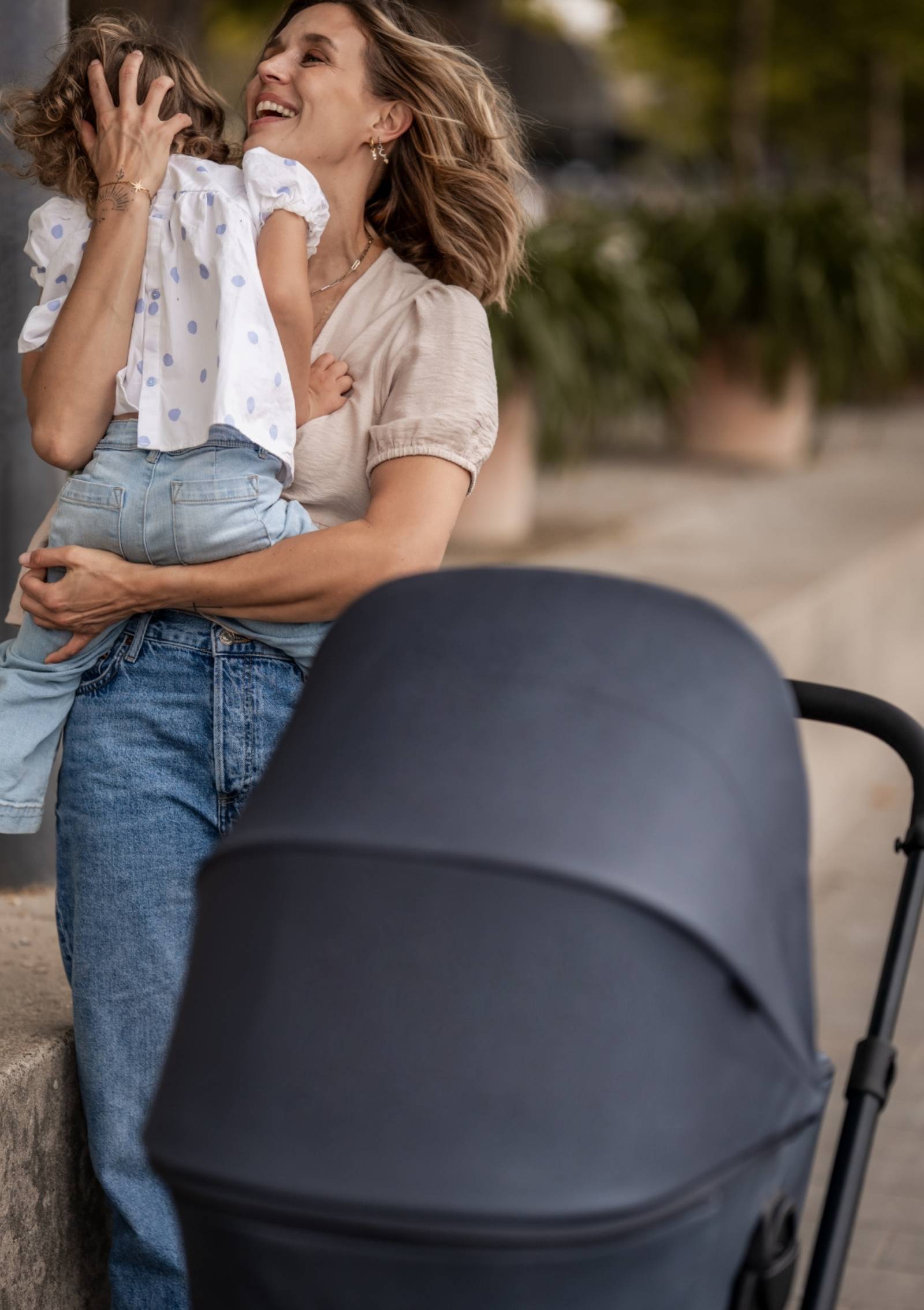 Frau trägt Kind – Easywalker Kinderwagen-Set 'Harvey NXT' Deep Blue inkl. Regenverdeck 