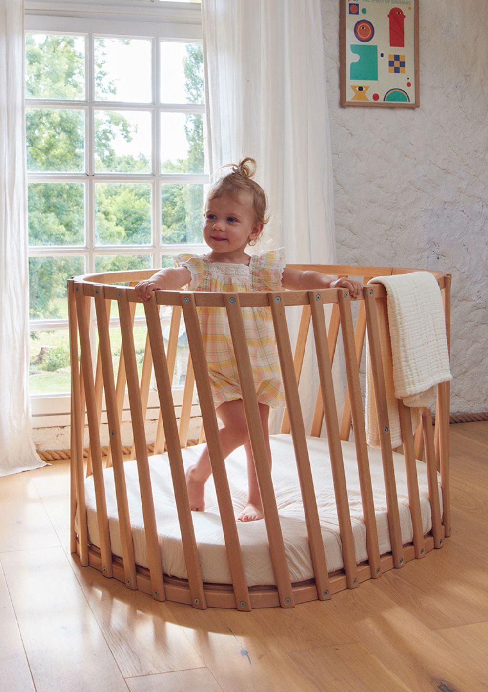 Mädchen steht im Charlie Crane Babybett 'Lugo' 90 x 70 cm