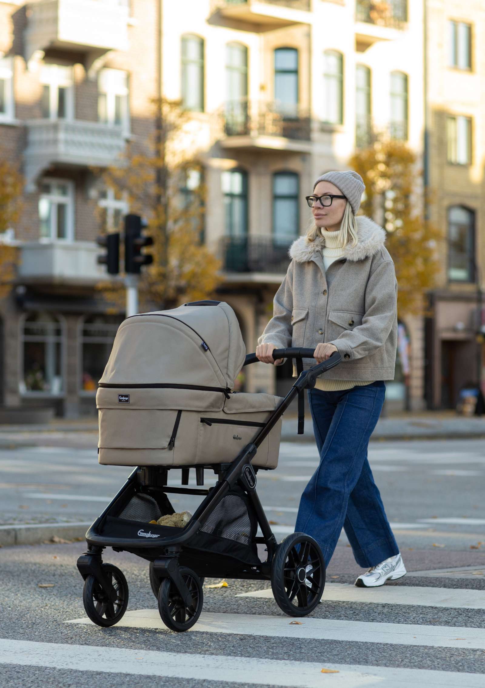 Frau schiebt Emmaljunga Kinderwagen 'SENTO PRO' Urban Dune über die Straße