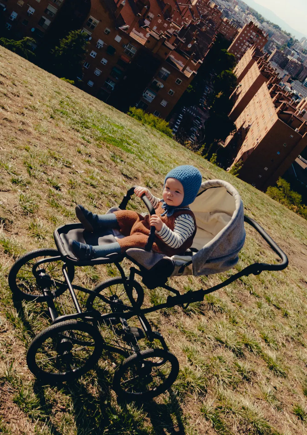 Kleinkind sitzt im Sportsitz des Angelcab Kinderwagen-Sets 'C3-Series' Upminster auf einer Stadtparkwiese