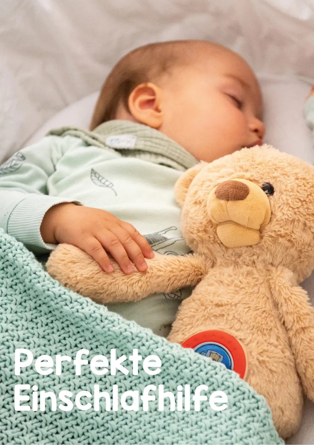 Schlafendes Baby liegt kuschelnd mit dem Theodore KekzBär im Bett